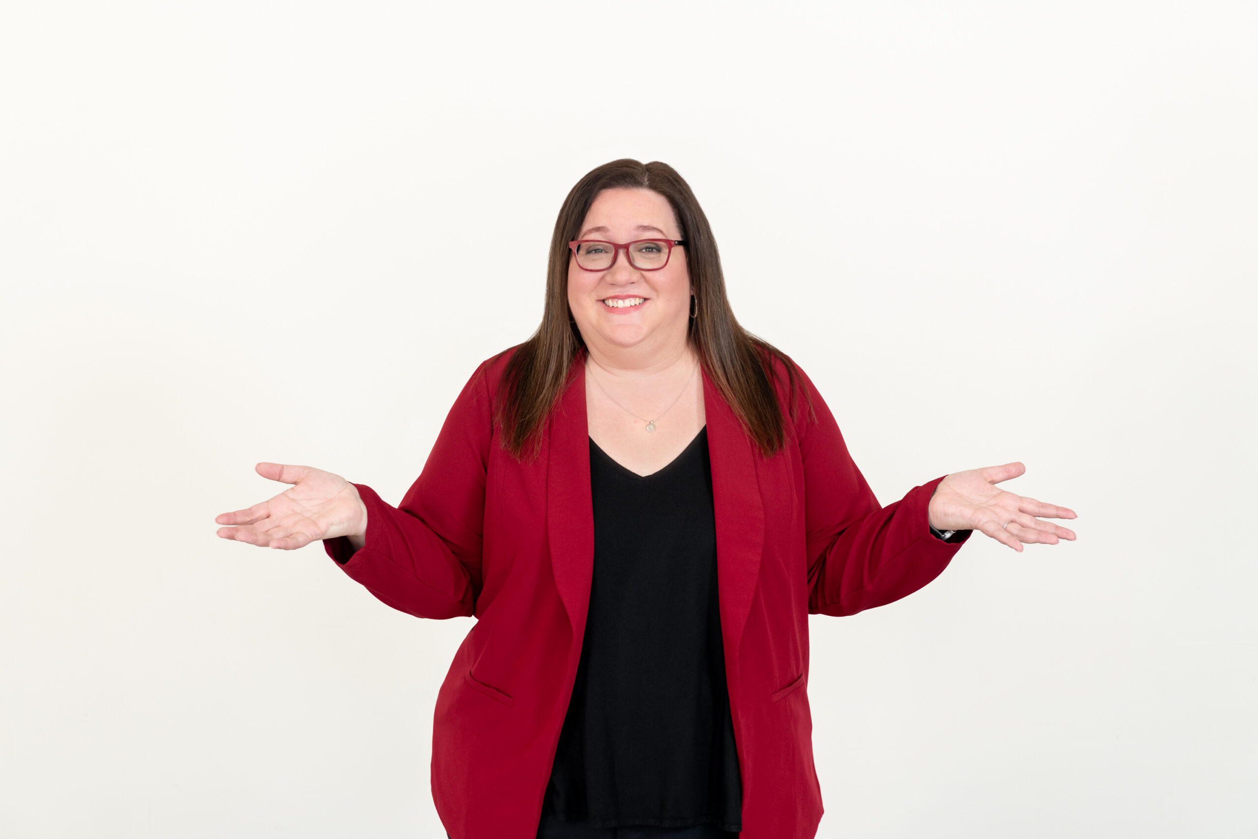 Amy K. Nunn in a red blazer with her hands open, inviting the conversation.