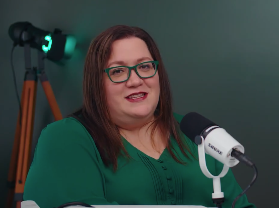 Amy K. Nunn smiling at her microphone in the podcast studio.